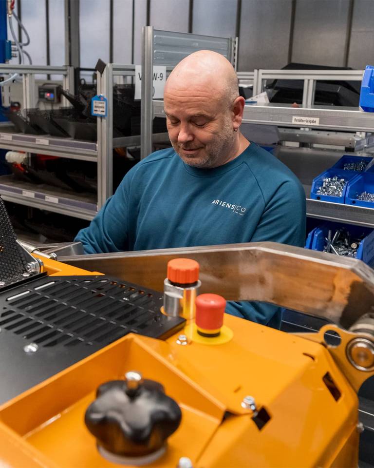 Factory worker of AriensCo EMEAA wearing their new turquise work wear inside their factory in Bühlertann, Germany